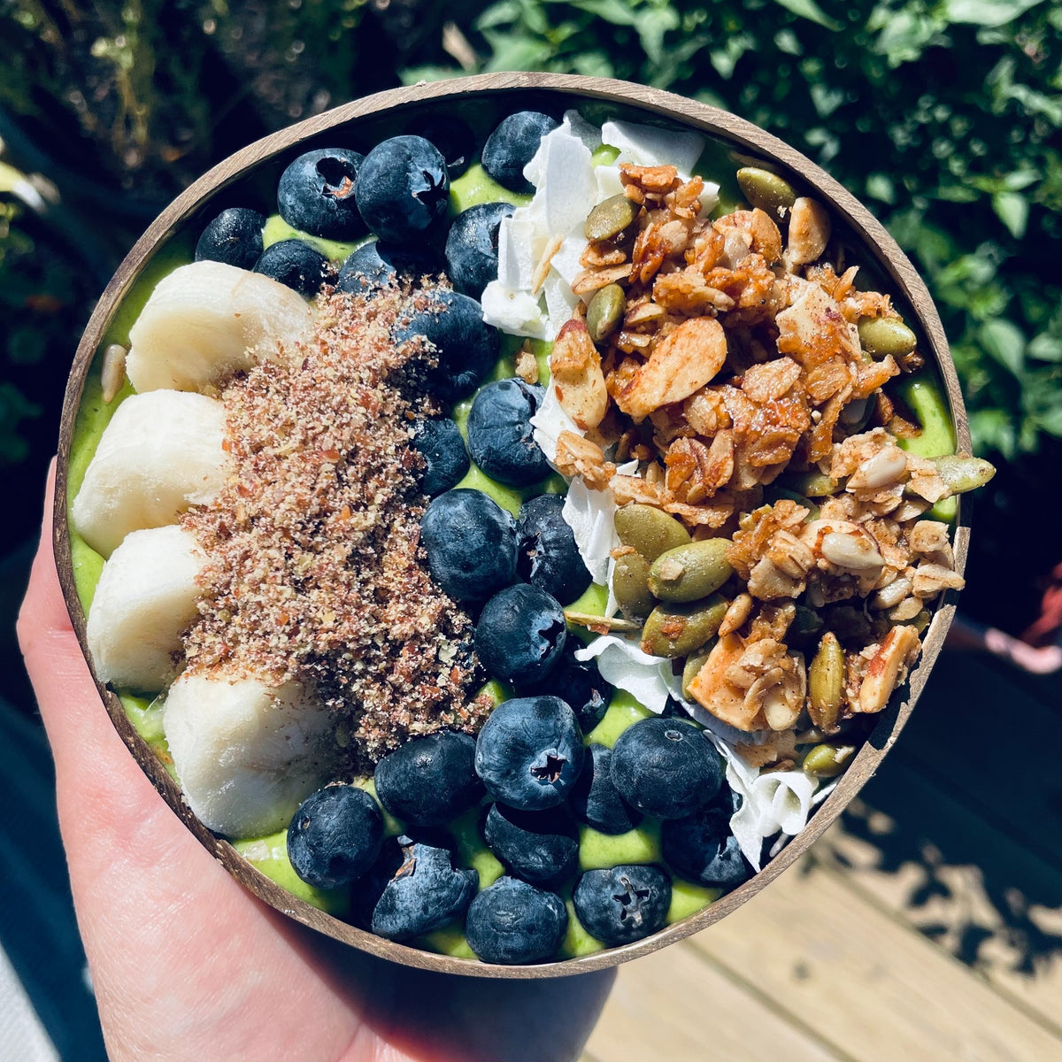 Maple Cinnamon granola served on a power greens smoothie bowl with fruit, coconut and ground flax